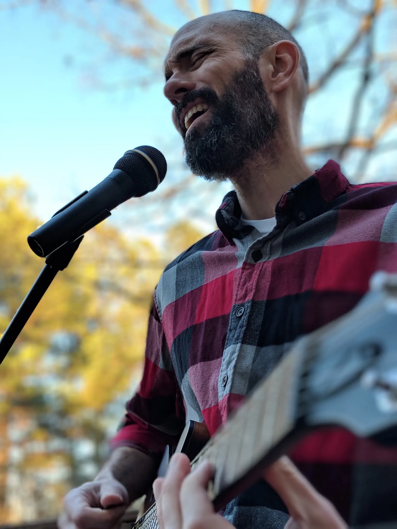Nathan Hughes singing into a mic with an acoustic guitar